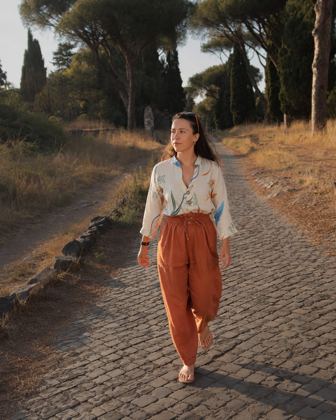 Erica Ferrari Trecate walking along a Mediterranean path at sunset.